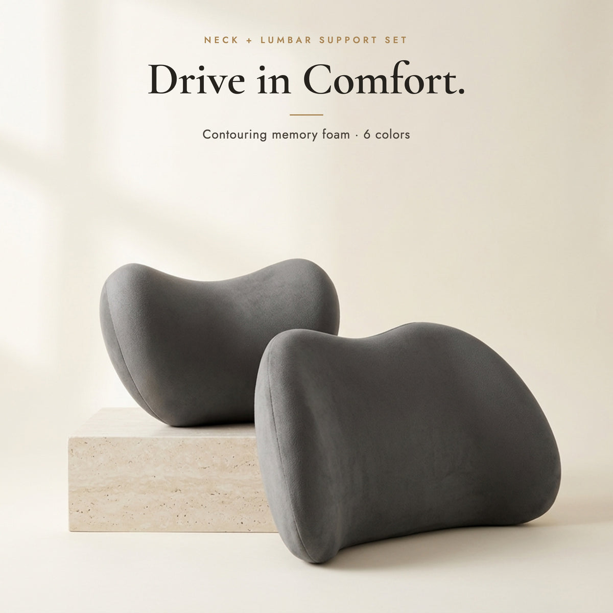 Dark grey neck pillow and lumbar pillow on a stone block on an ivory background