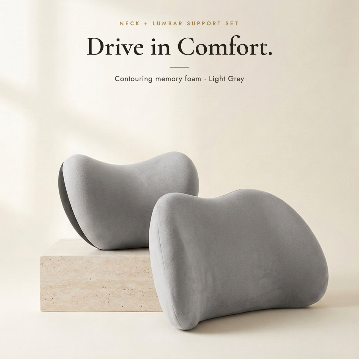 Light grey neck pillow and lumbar pillow on an ivory background